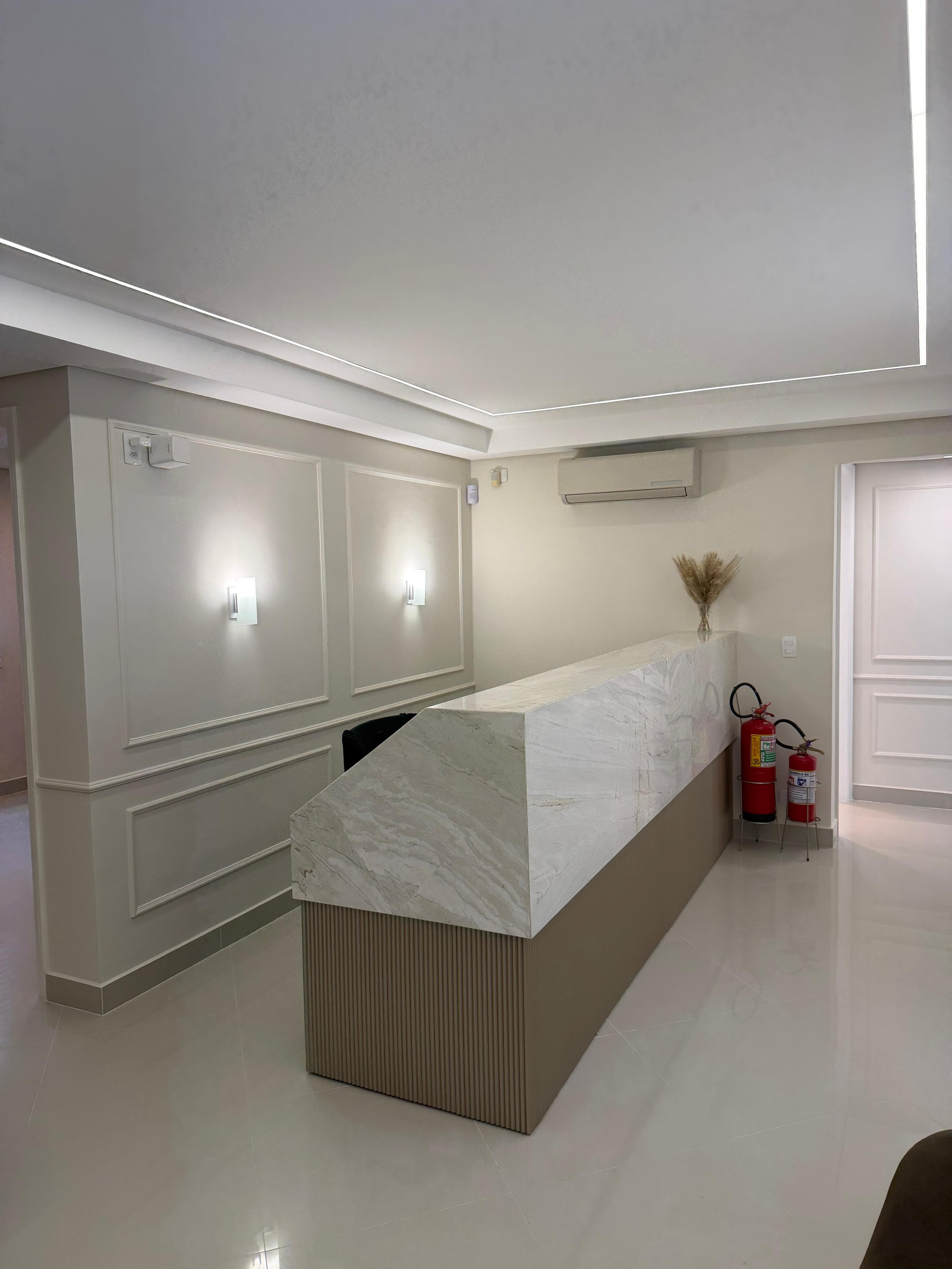 Recepção da Clínica Shwetz com balcão em mármore e iluminação integrada