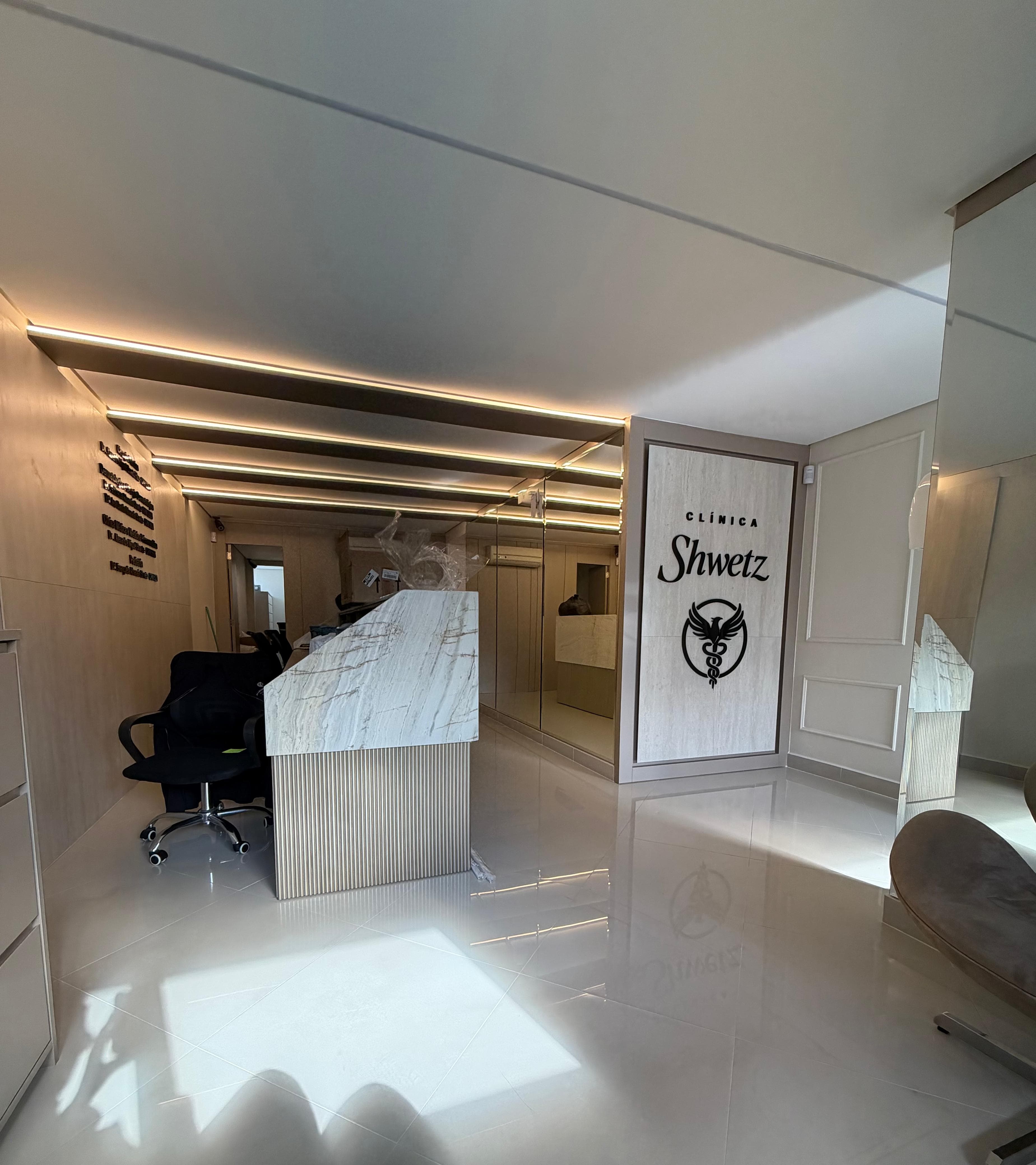 Recepção da Clínica Shwetz com logotipo na parede e piso espelhado